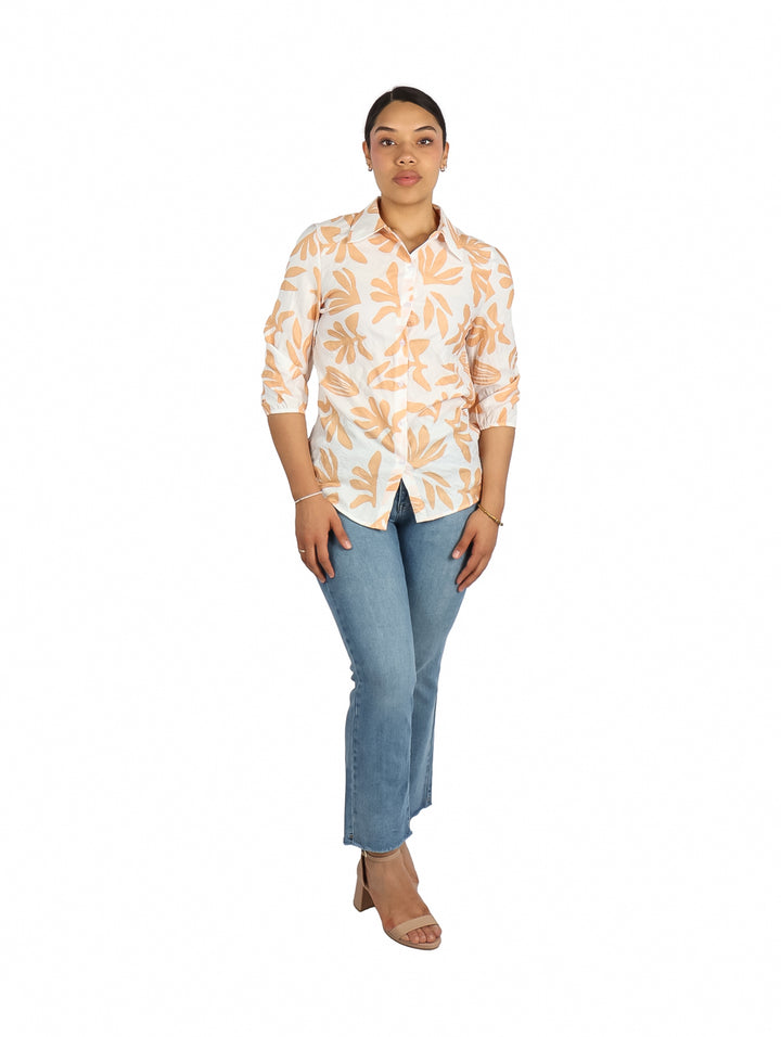 Mujer vistiendo camisa blanca de manga corta con estampado de hojas naranjas.