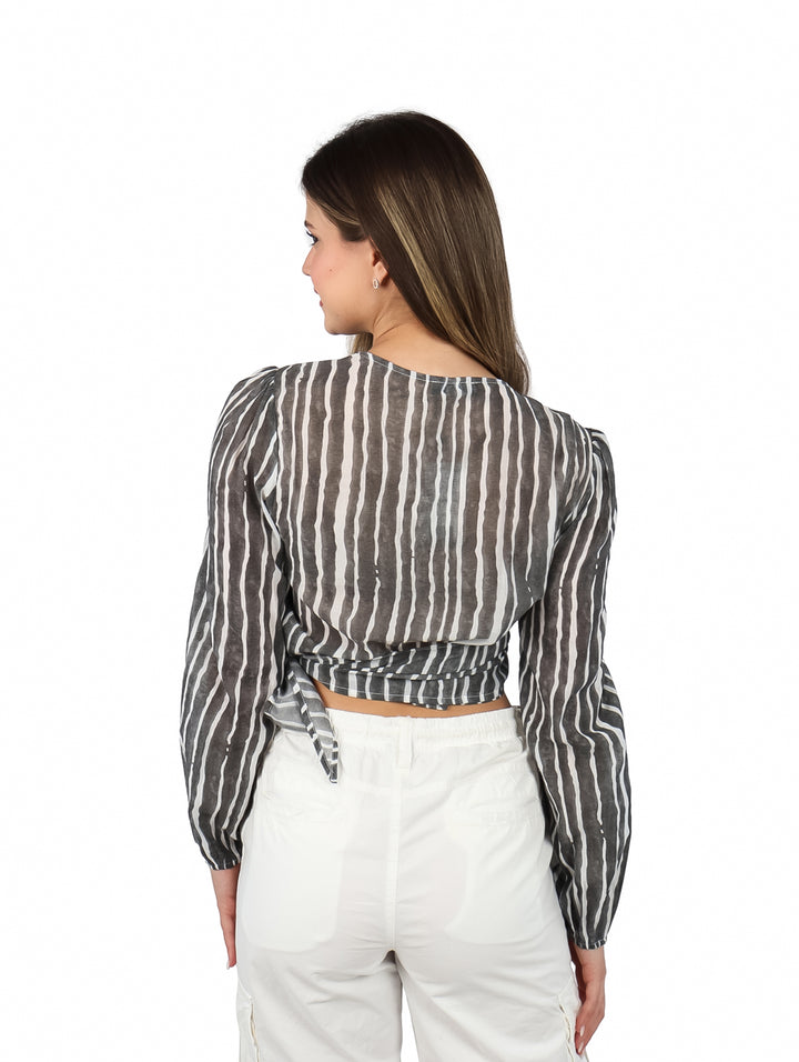 Mujer vistiendo blusa corta ATOK a rayas verticales blancas y negras con cuello en V y pantalones blancos.