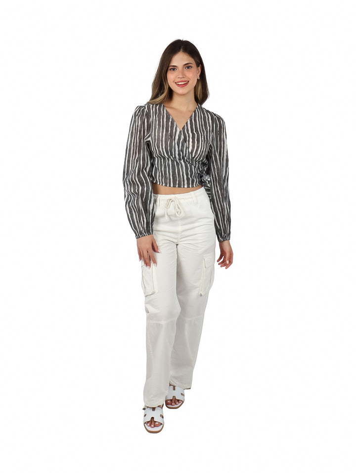 Mujer vistiendo blusa corta ATOK a rayas verticales blancas y negras con cuello en V y pantalones blancos.