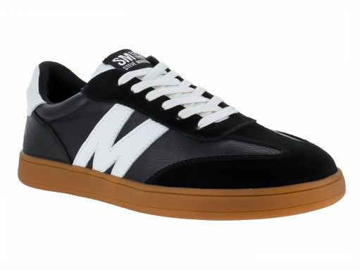 Tenis Steve Madden Caelum en color negro con detalles blancos y suela marrón caramelo.