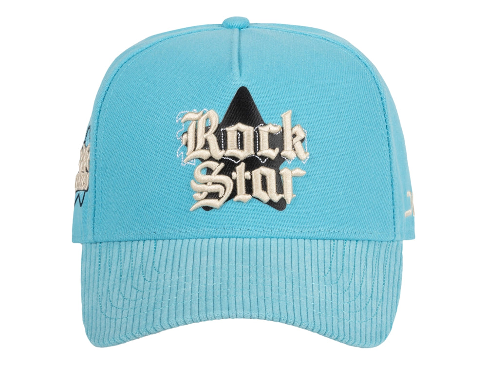 Gorra snapback color azul celeste con bordado frontal que dice Rock Star y logotipo JC en el lateral.