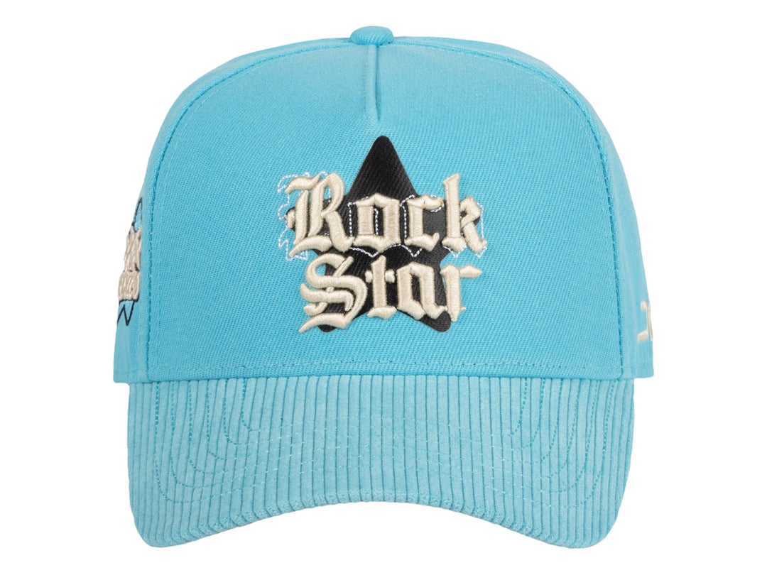 Gorra snapback color azul celeste con bordado frontal que dice Rock Star y logotipo JC en el lateral.