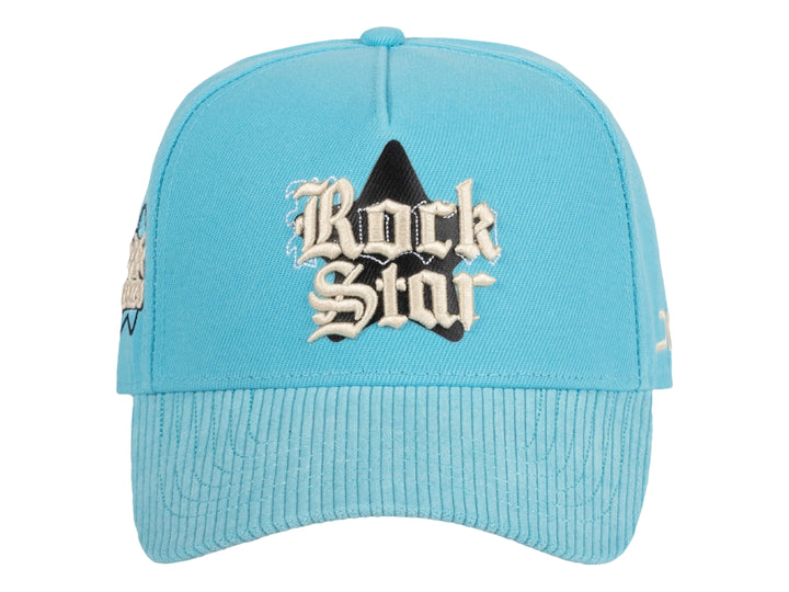 Gorra snapback color azul celeste con bordado frontal que dice Rock Star y logotipo JC en el lateral.