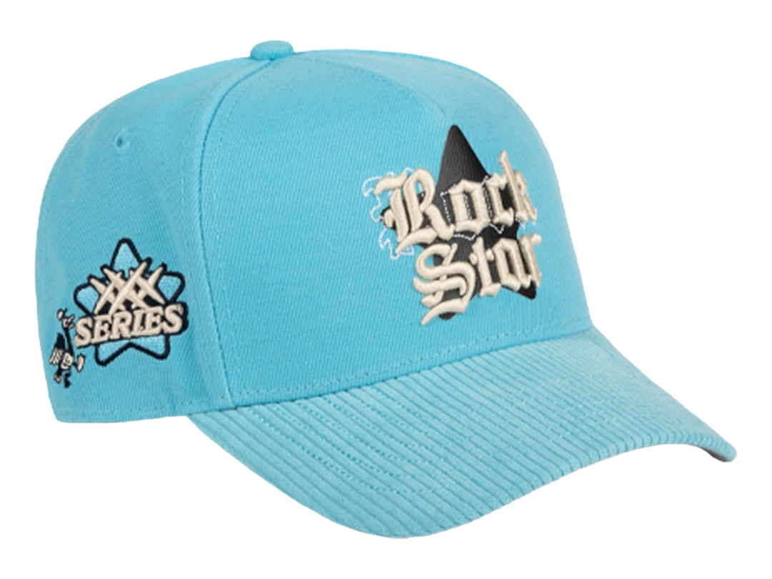 Gorra snapback color azul celeste con bordado frontal que dice Rock Star y logotipo JC en el lateral.