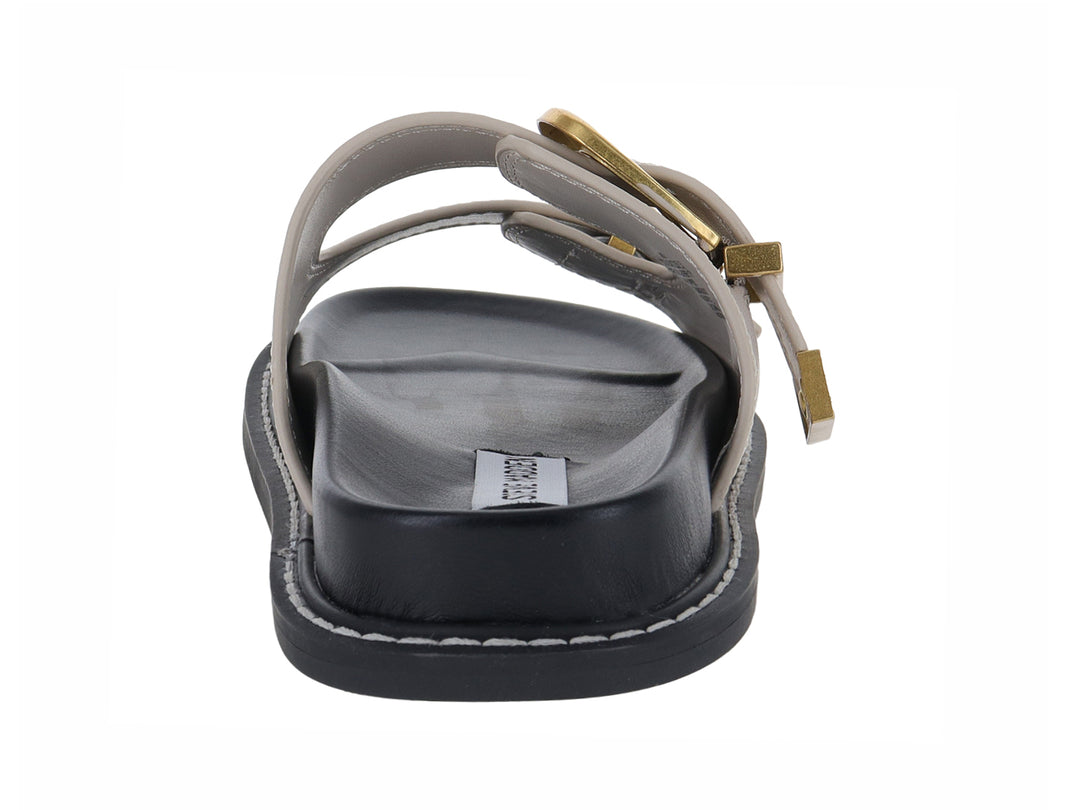 Sandalia plana Steve Madden color beige con dos correas, hebillas doradas y suela negra.