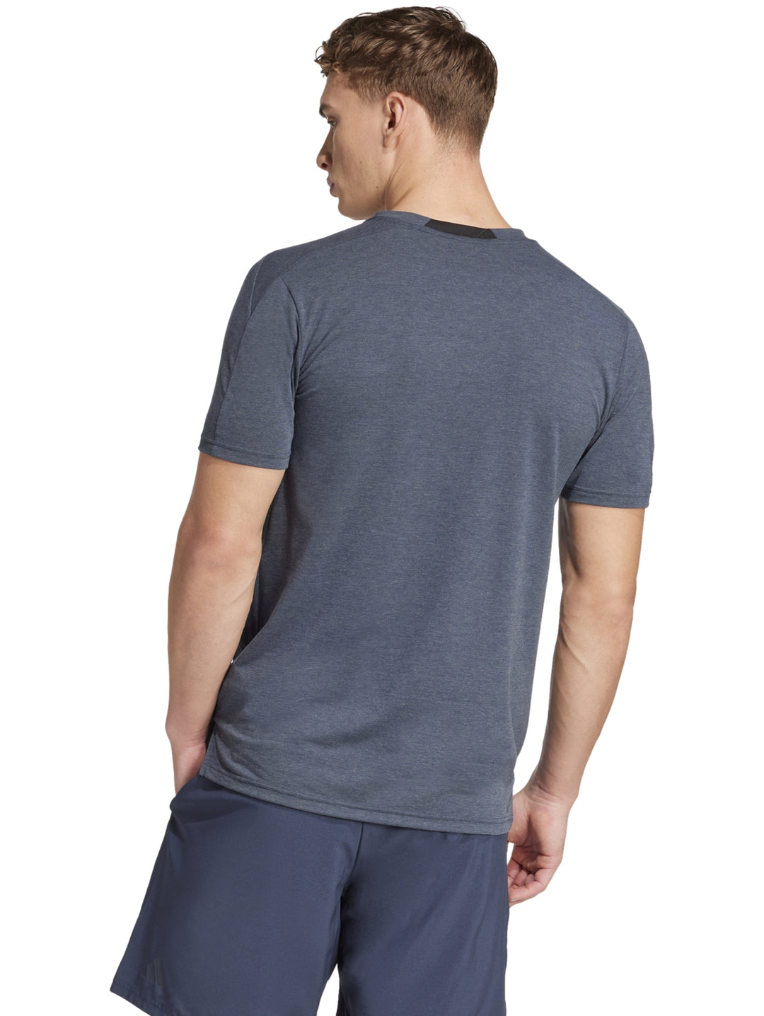 Hombre vistiendo una camiseta deportiva Adidas de color gris con cuello redondo y manga corta.