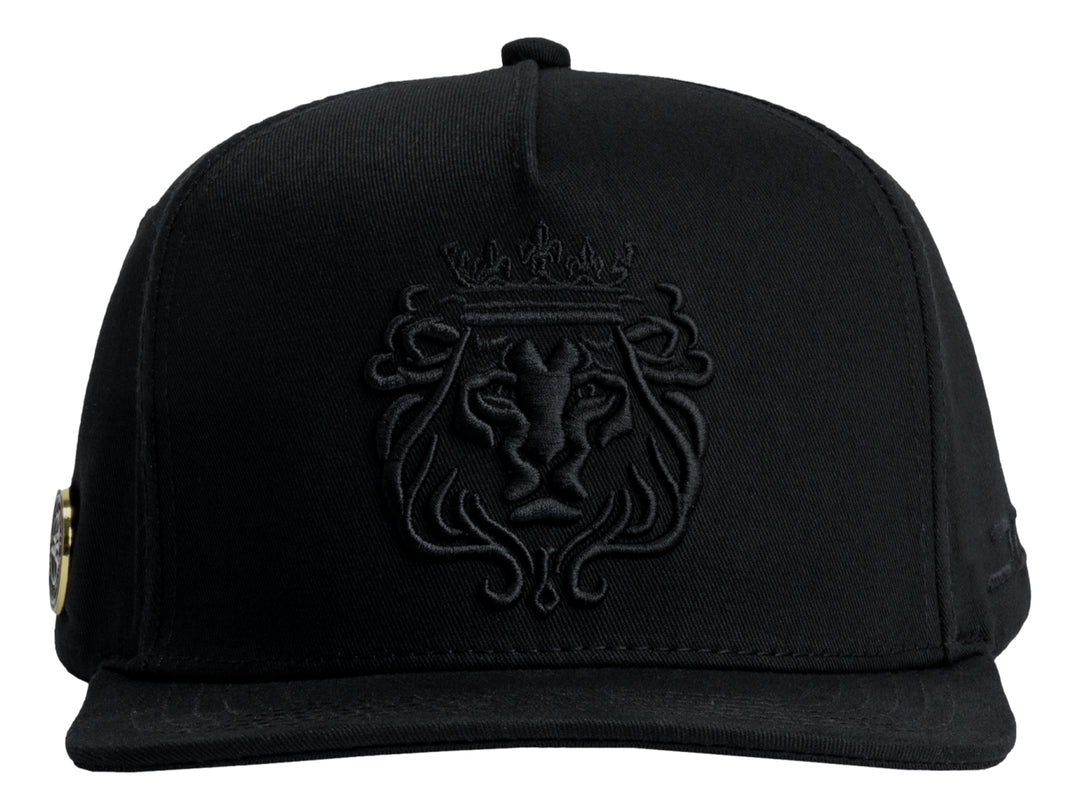 Gorra JC HATS color negro con bordado frontal en relieve de un león con corona.