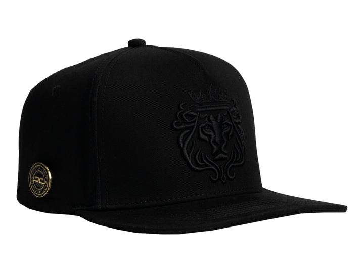 Gorra JC HATS color negro con bordado frontal en relieve de un león con corona.
