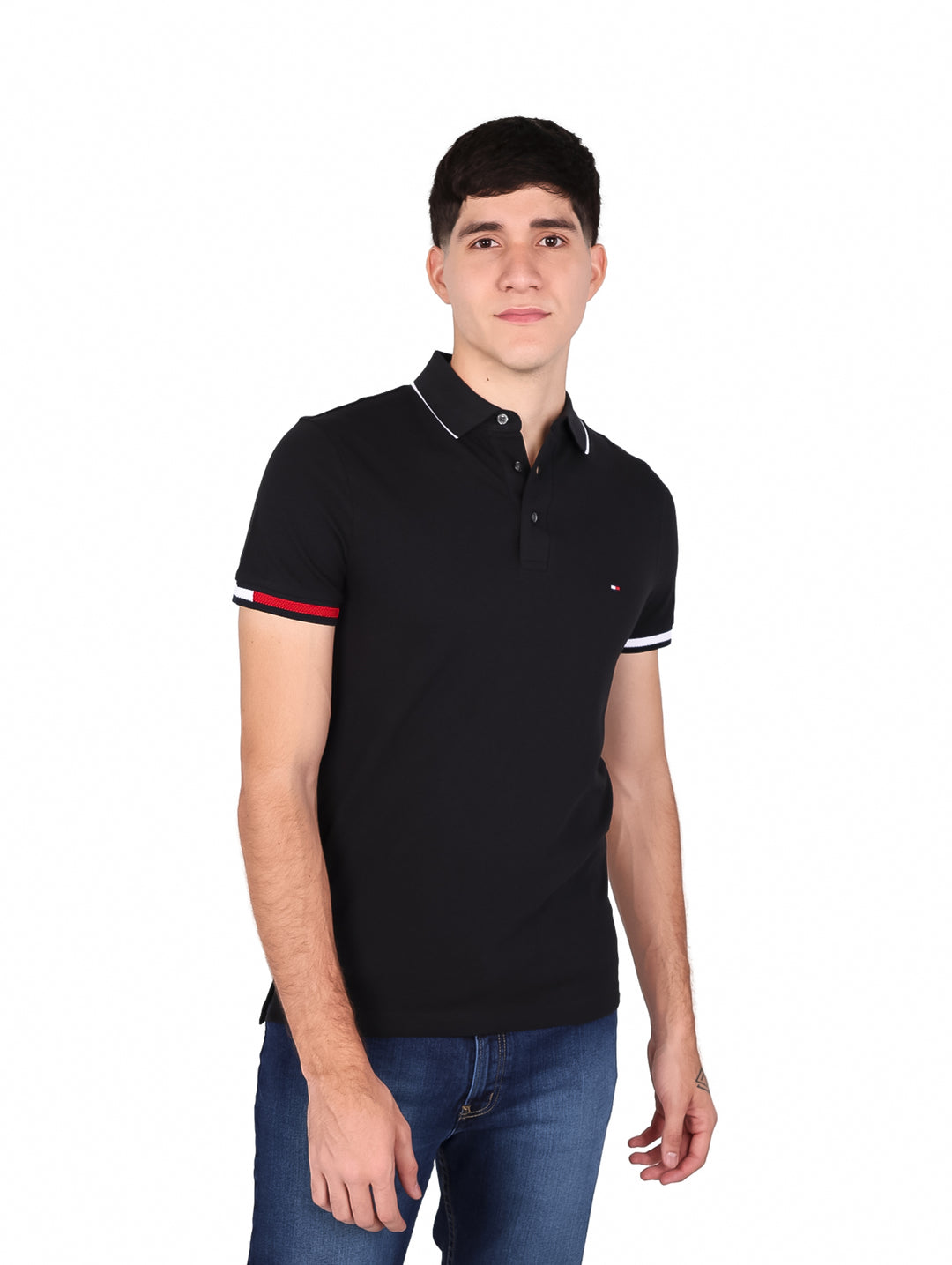 Hombre vistiendo polo negro Slim Fit de Tommy Hilfiger con detalles rojos y blancos en puños y cuello.