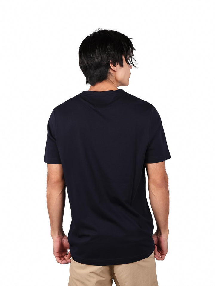 Hombre vistiendo camiseta azul marino de manga corta con texto de Tommy Hilfiger en el pecho.