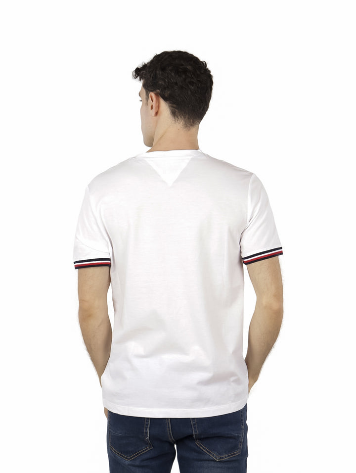 Hombre vistiendo una camiseta blanca de manga corta con rayas en los puños y un pequeño logo en el pecho.