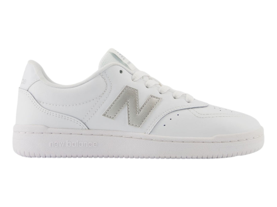 Tenis New Balance color blanco con logotipo en plata y suela blanca, vista lateral.