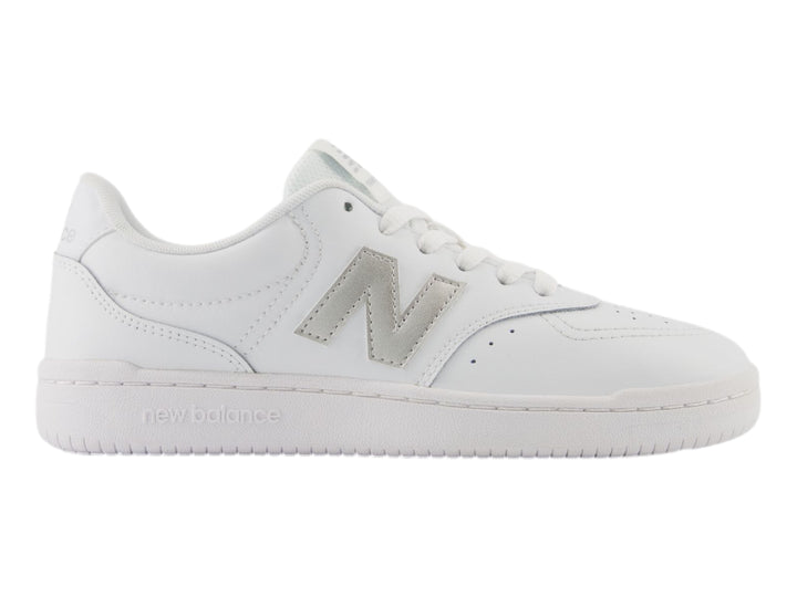 Tenis New Balance color blanco con logotipo en plata y suela blanca, vista lateral.