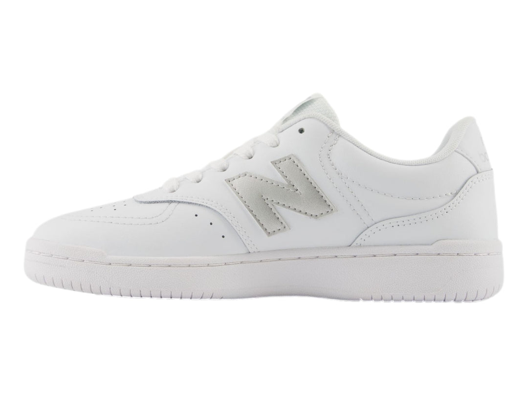 Tenis New Balance color blanco con logotipo en plata y suela blanca, vista lateral.