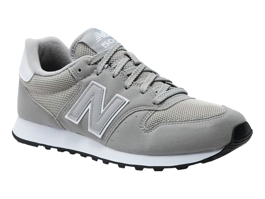 Tenis New Balance color gris con suela blanca y detalles en malla y gamuza.