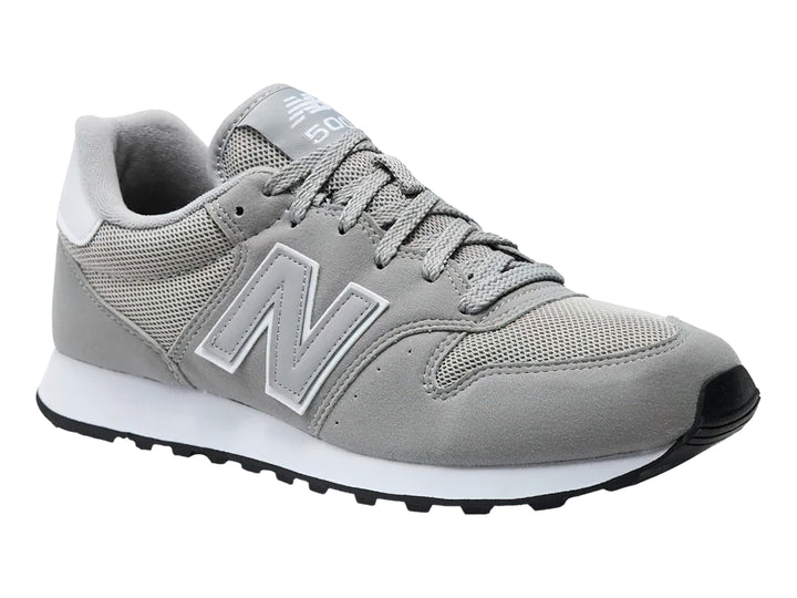Tenis New Balance color gris con suela blanca y detalles en malla y gamuza.