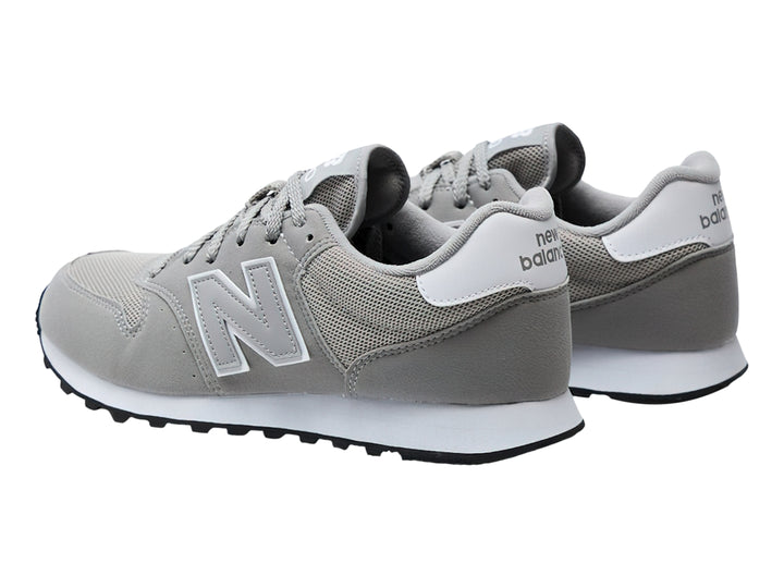 Tenis New Balance color gris con suela blanca y detalles en malla y gamuza.