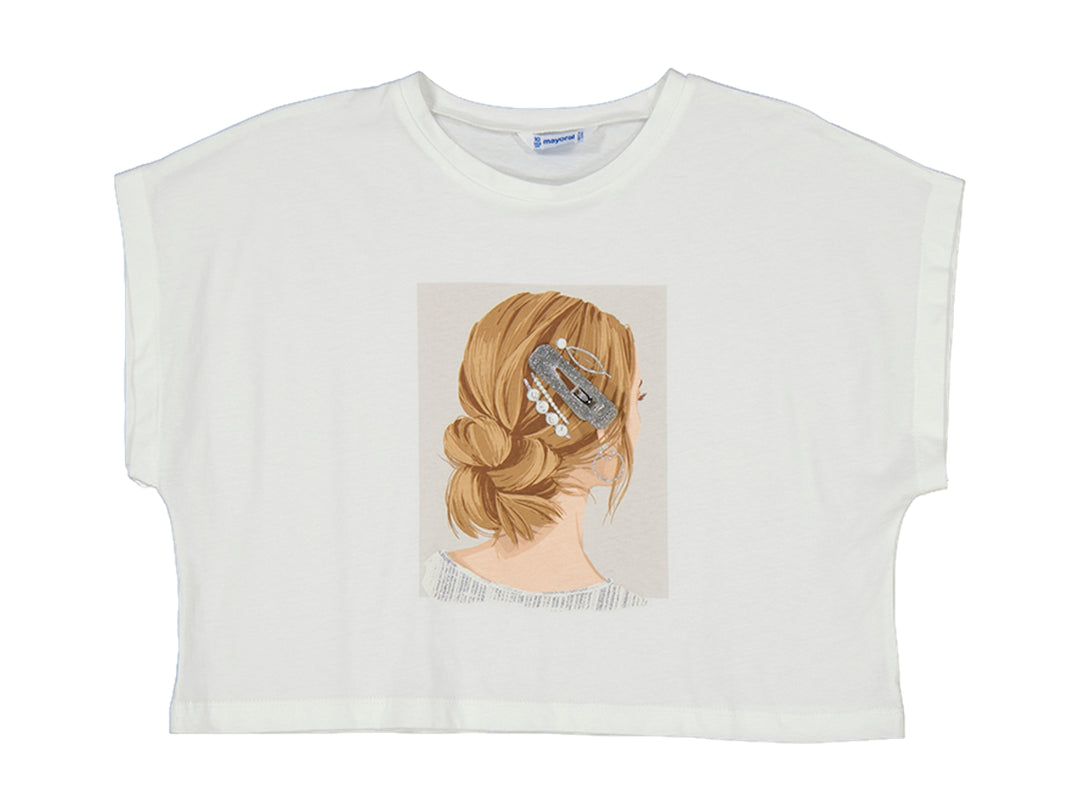 Camiseta corta color crudo con estampado central de una niña con el cabello recogido y pinzas.