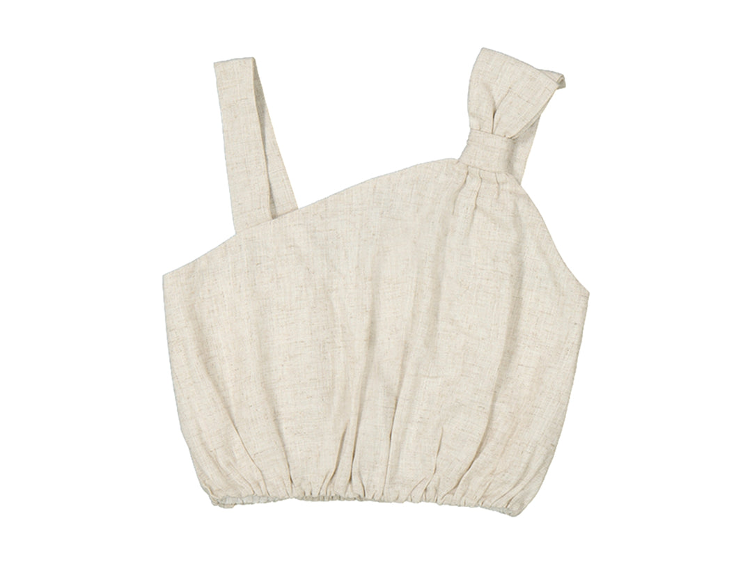 Top de lino color beige para niña con diseño asimétrico y detalle de lazo en el hombro.