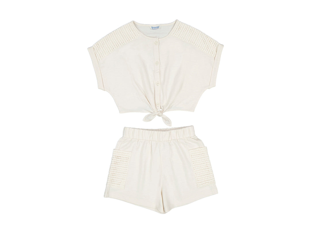 Conjunto de ropa infantil color hueso con top de botones y nudo frontal y shorts coordinados.