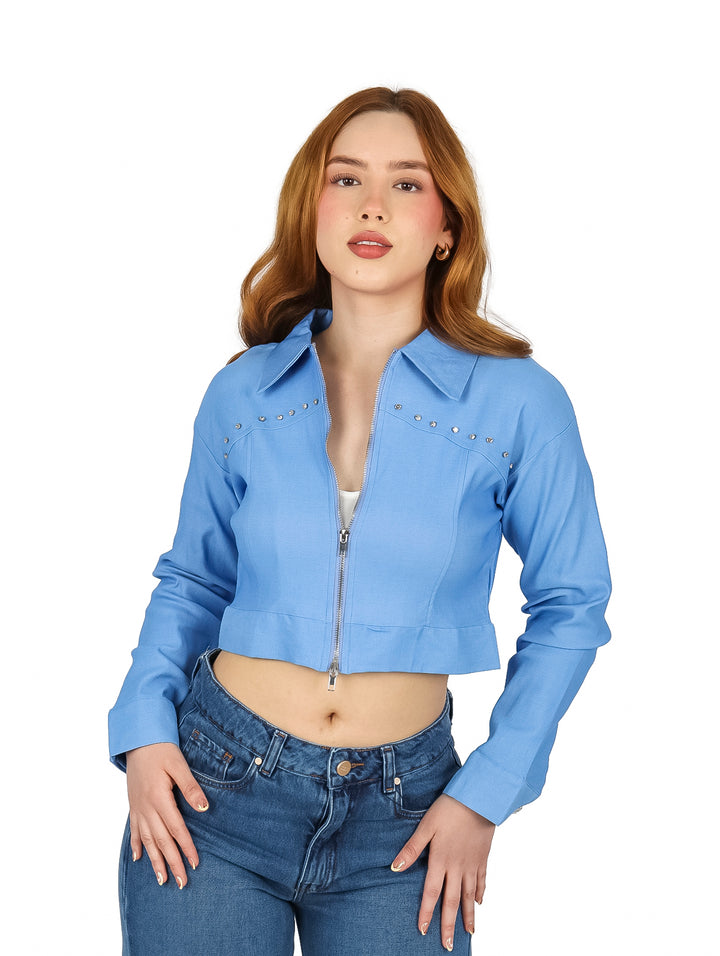 Mujer vistiendo una chaqueta corta color azul con estoperoles plateados y cierre frontal.