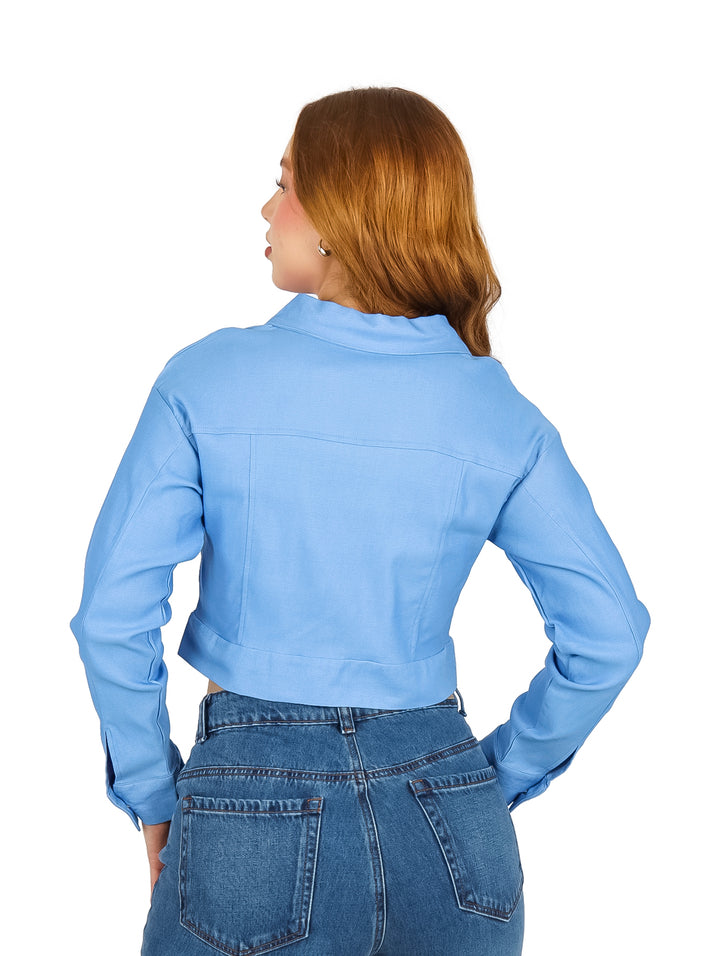 Mujer vistiendo una chaqueta corta color azul con estoperoles plateados y cierre frontal.
