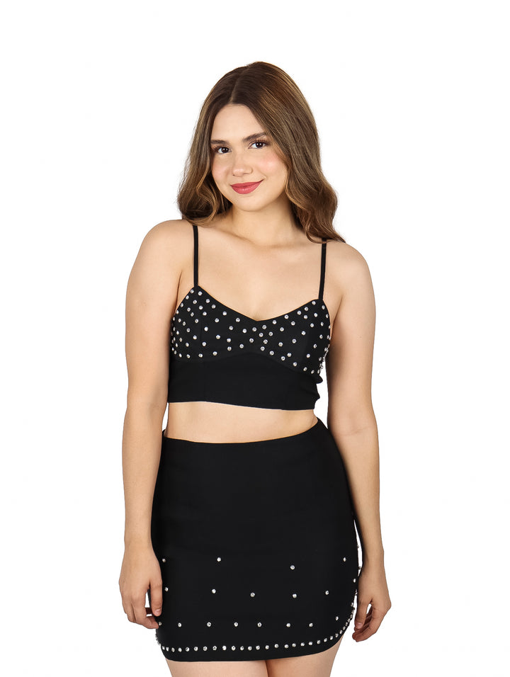 Crop top negro con estoperoles plateados y tirantes delgados.