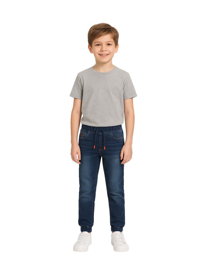 Niño vistiendo pantalones jogger de mezclilla azul con cintura elástica y cordones.