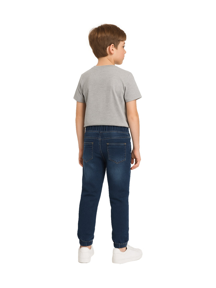 Niño vistiendo pantalones jogger de mezclilla azul con cintura elástica y cordones.
