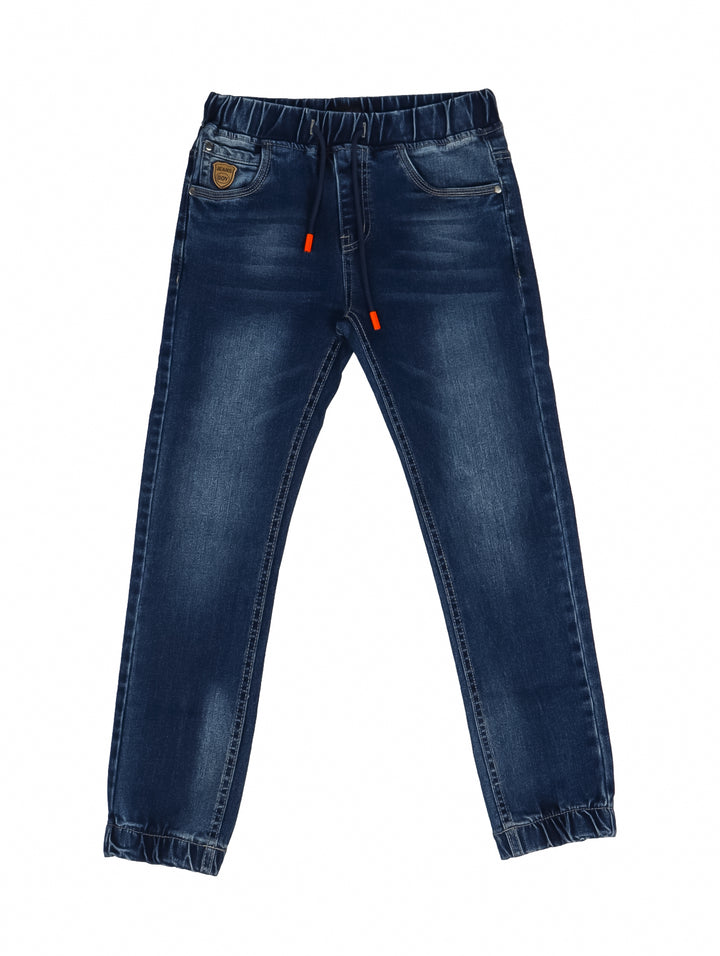 Niño vistiendo pantalones jogger de mezclilla azul con cintura elástica y cordones.
