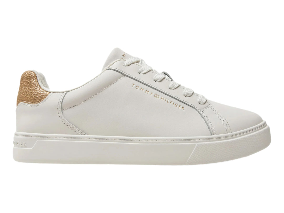 Tenis Tommy Hilfiger color ecru con detalle dorado metálico en el talón.