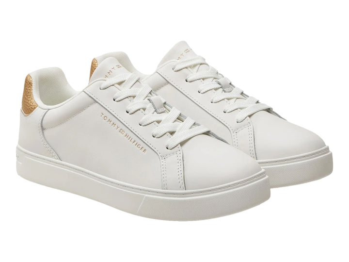 Tenis Tommy Hilfiger color ecru con detalle dorado metálico en el talón.