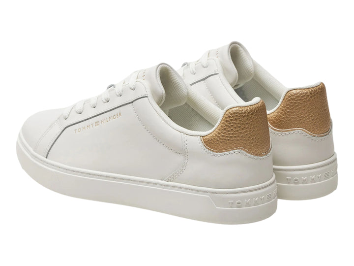 Tenis Tommy Hilfiger color ecru con detalle dorado metálico en el talón.