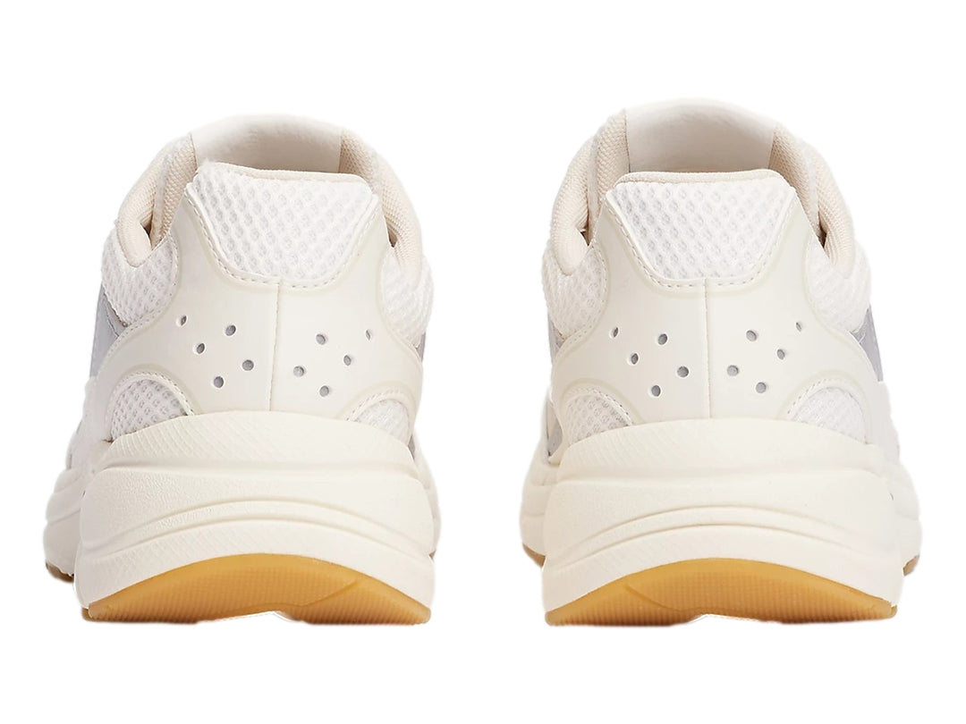 Tenis deportivos Tommy Hilfiger color blanco hueso con detalles plateados y suela de goma marrón.