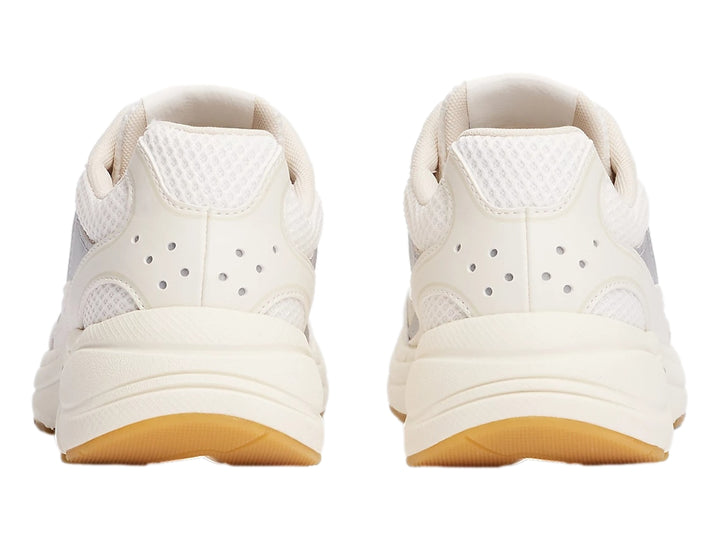 Tenis deportivos Tommy Hilfiger color blanco hueso con detalles plateados y suela de goma marrón.