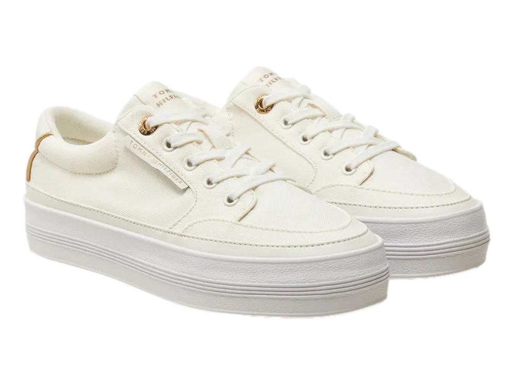 Tenis Tommy Hilfiger color ecru con suela de plataforma blanca y detalles dorados.