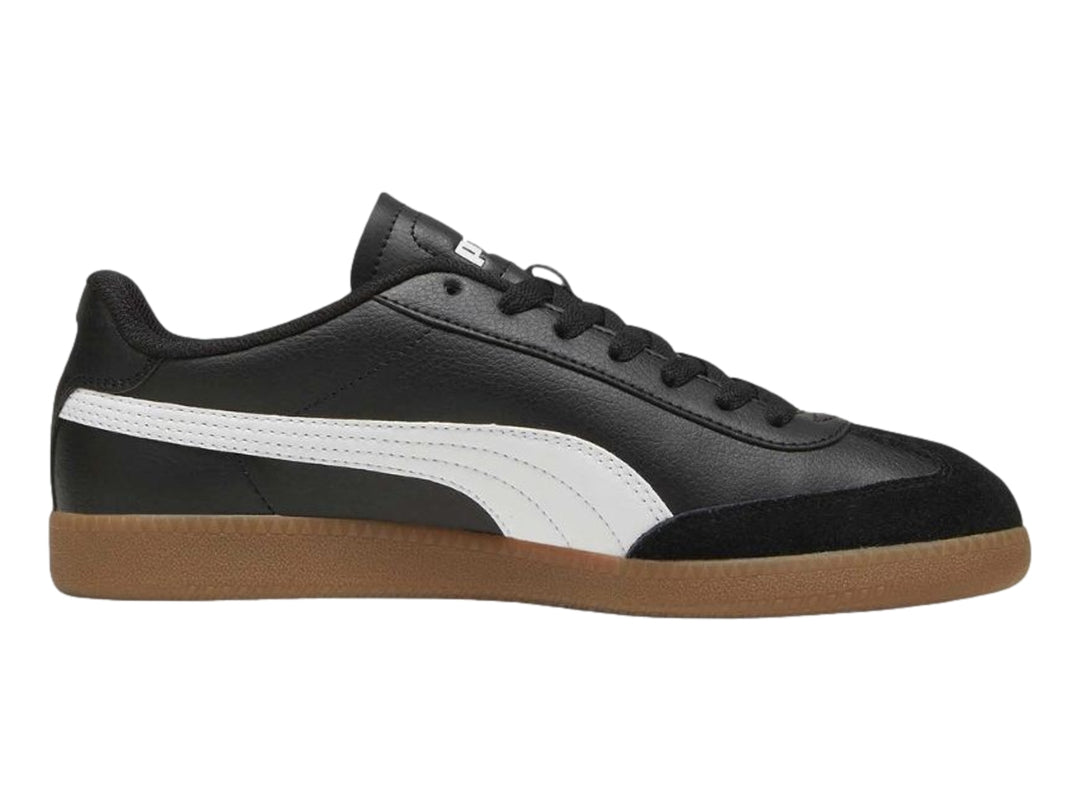 Tenis PUMA negros con franja blanca lateral y suela de goma color marrón.