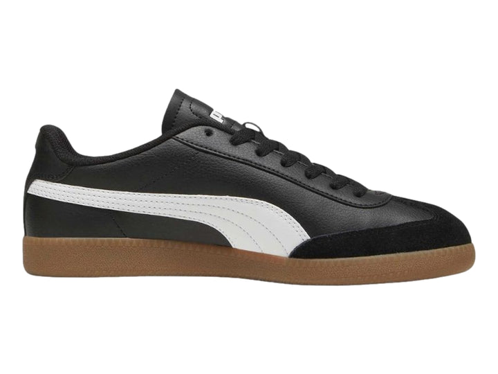 Tenis PUMA negros con franja blanca lateral y suela de goma color marrón.