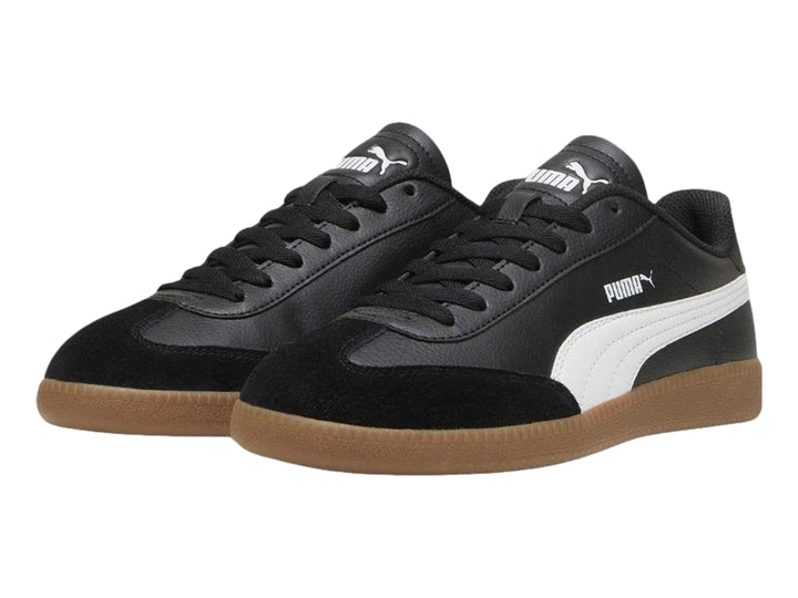 Tenis PUMA negros con franja blanca lateral y suela de goma color marrón.