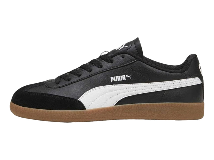 Tenis PUMA negros con franja blanca lateral y suela de goma color marrón.