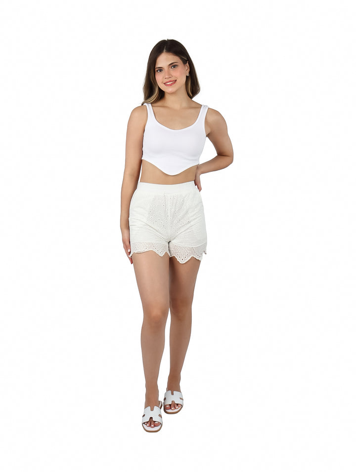 Mujer vistiendo shorts cortos de color blanco con detalles de encaje y perforaciones.