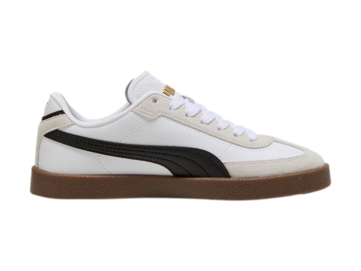 Tenis PUMA blancos para niños con franja negra lateral y suela de goma marrón.