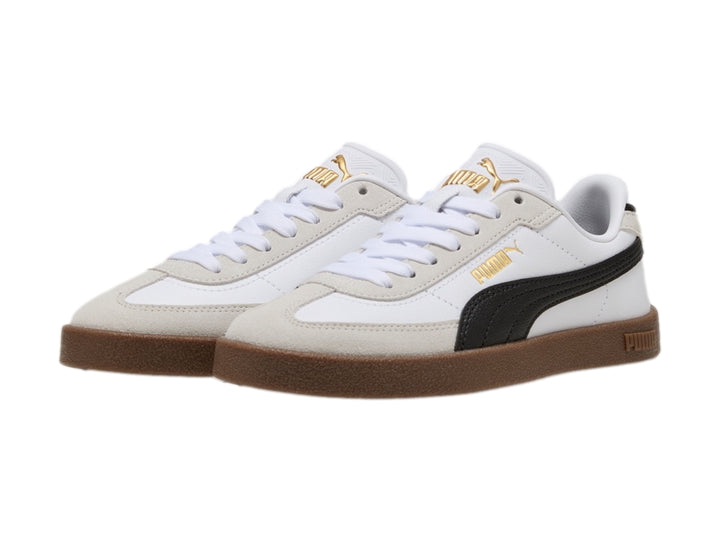 Tenis PUMA blancos para niños con franja negra lateral y suela de goma marrón.