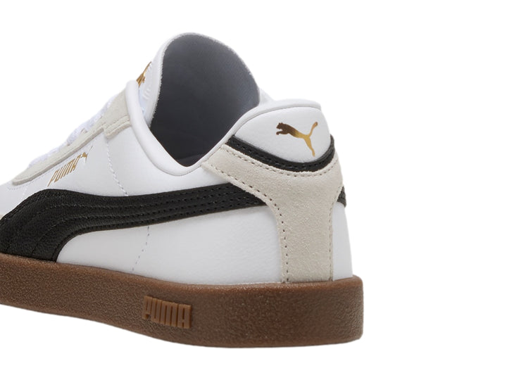 Tenis PUMA blancos para niños con franja negra lateral y suela de goma marrón.