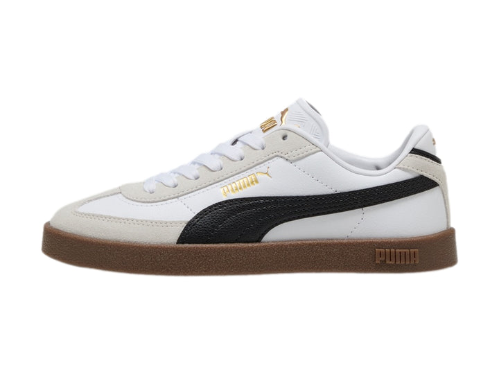 Tenis PUMA blancos para niños con franja negra lateral y suela de goma marrón.