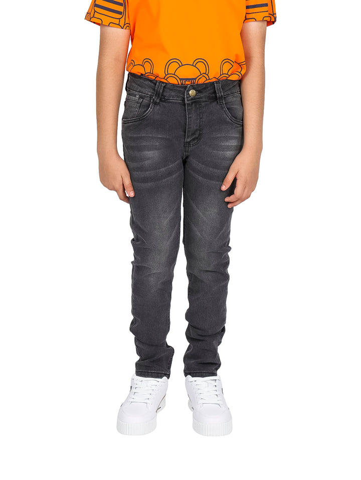 Pantalones vaqueros rectos de color negro para niño, combinados con camiseta naranja y tenis blancos.