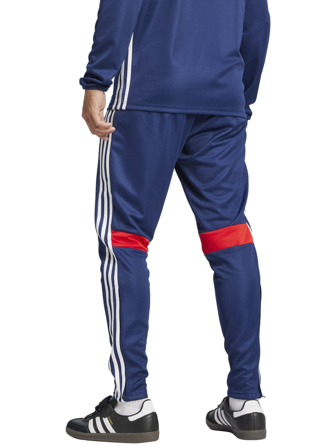 Pantalón deportivo Adidas azul marino con franjas blancas laterales y un pequeño detalle rojo en la pierna.