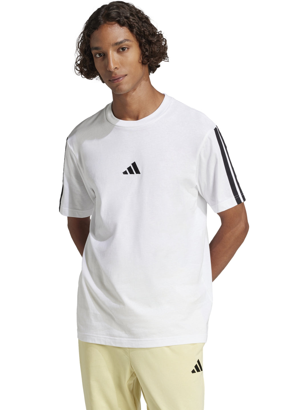 Hombre vistiendo playera Adidas blanca con tres franjas negras en los hombros y logo en el pecho.