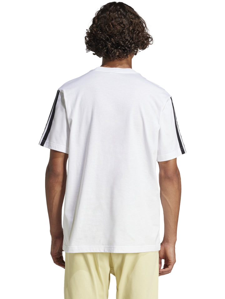 Hombre vistiendo playera Adidas blanca con tres franjas negras en los hombros y logo en el pecho.
