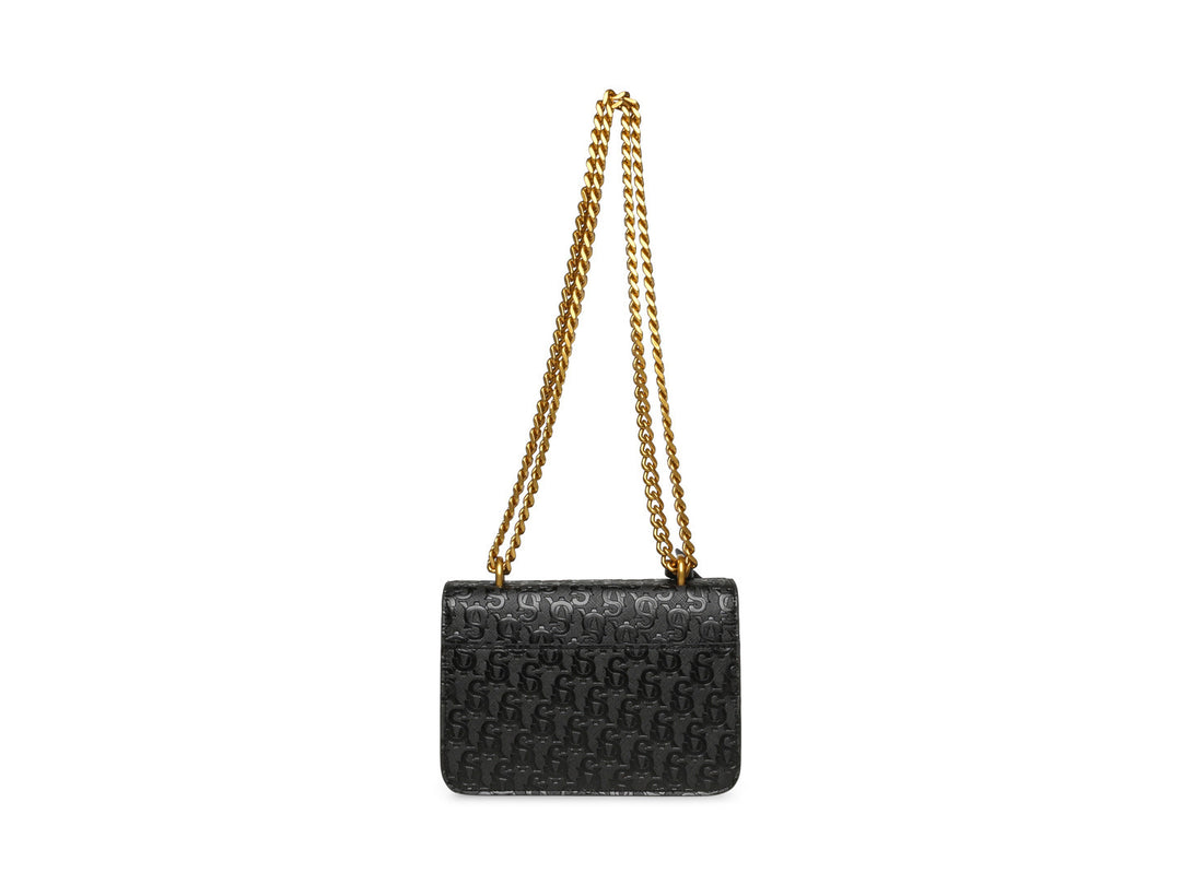 Bolso pequeño negro con acabado brillante y cadena dorada de la marca Steve Madden.